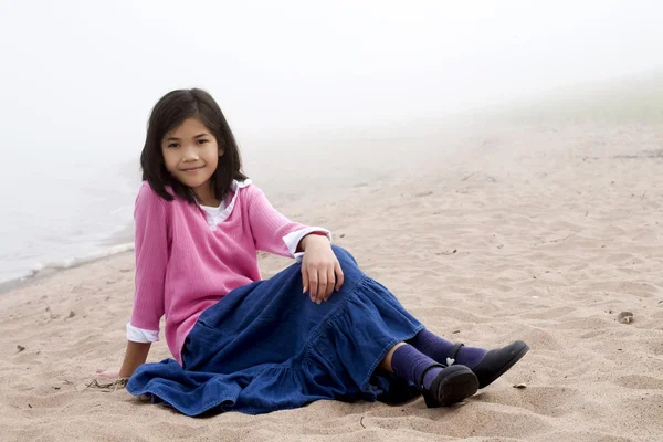 Giovane ragazza seduta sulla spiaggia — Foto Stock