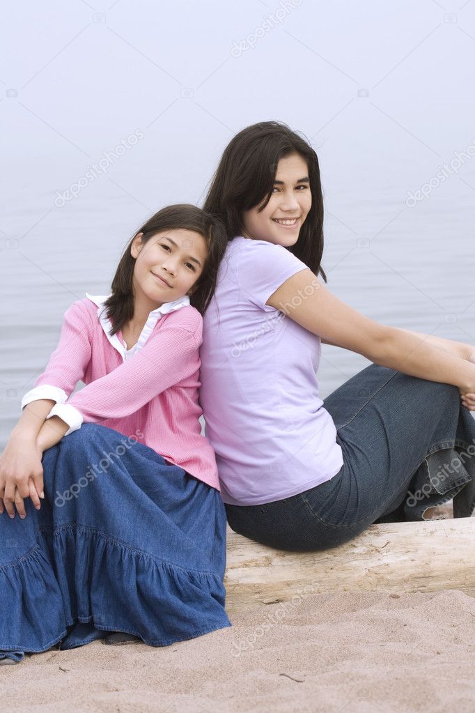 Two sisters sitting by beach