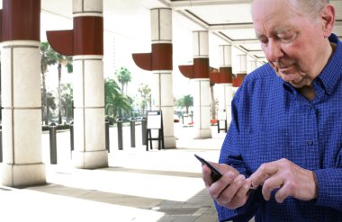 Elderly man dialing cell phone clipart