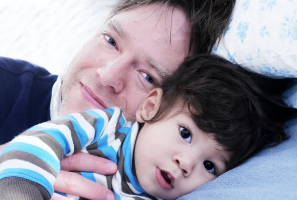 Pai e filho descansando na cama — Fotografia de Stock
