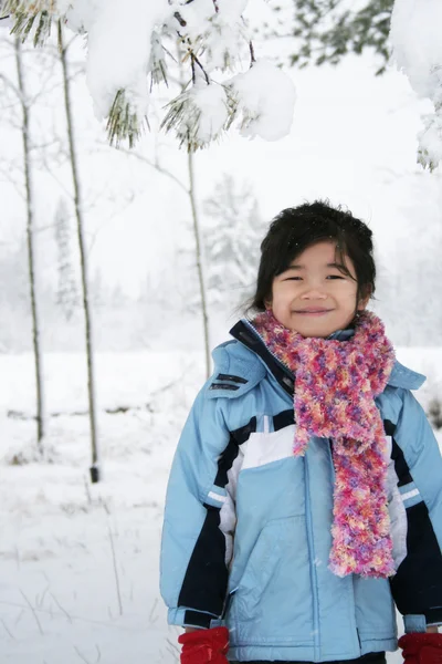 Kleines Mädchen unter schneebedeckten Bäumen — Stockfoto