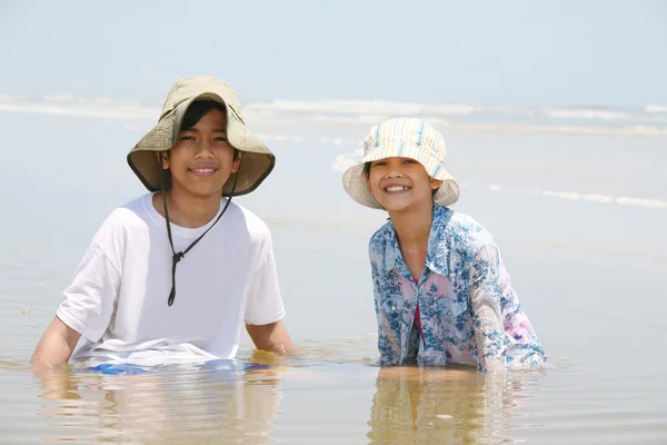 Двое детей сидят в воде у океана — стоковое фото