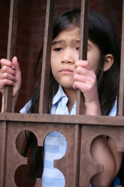 Little girl standing behind iron bars clipart