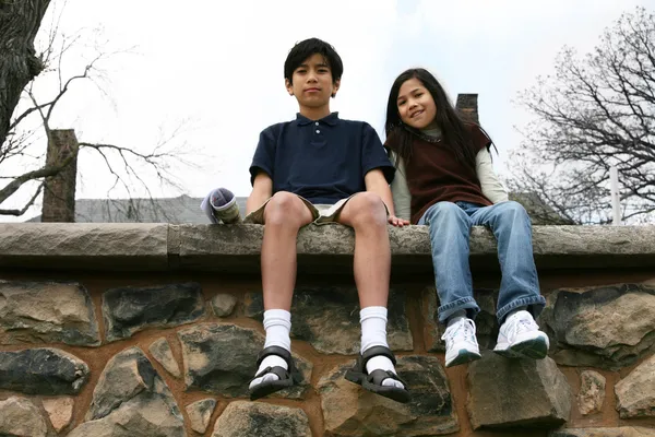 Dwoje dzieci siedząc na parapecie rock — Zdjęcie stockowe