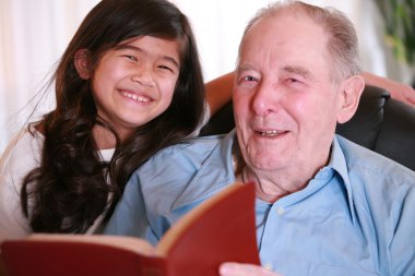 Elderly man and girl reading Bible clipart