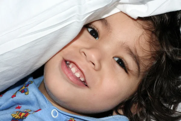 小さな男の子は枕の下ピーク — ストック写真