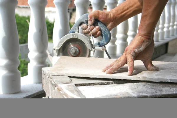 Um homem cortando um piso de cerâmica Imagens Royalty-Free