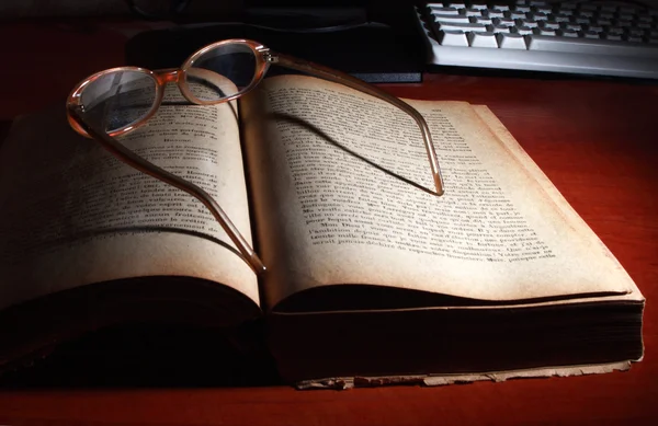 Старая книга, очки и клавиатура . — стоковое фото