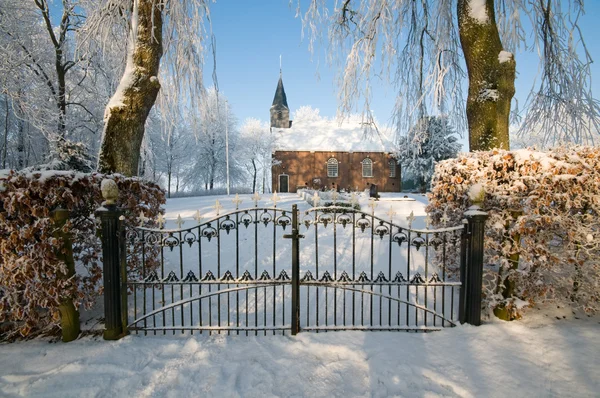 Kyrka bakom ett staket på vintern Stockbild