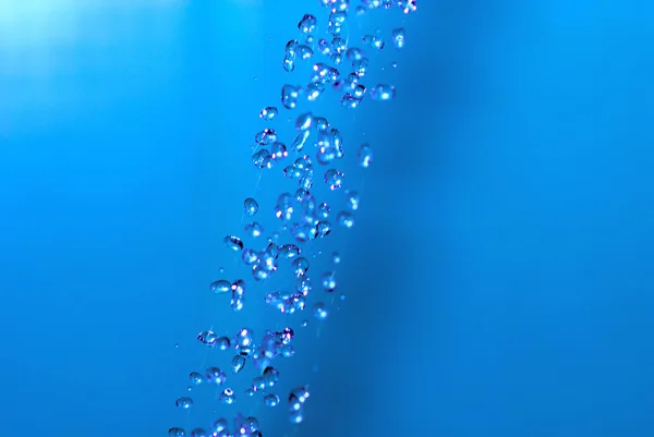 Jato de água sobre fundo azul — Fotografia de Stock