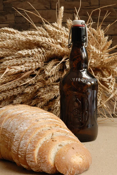 Pão fresco assado com hastes de trigo e garrafa de urso — Fotografia de Stock