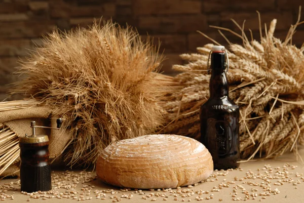 Pão fresco assado com hastes de trigo e garrafa de urso — Fotografia de Stock