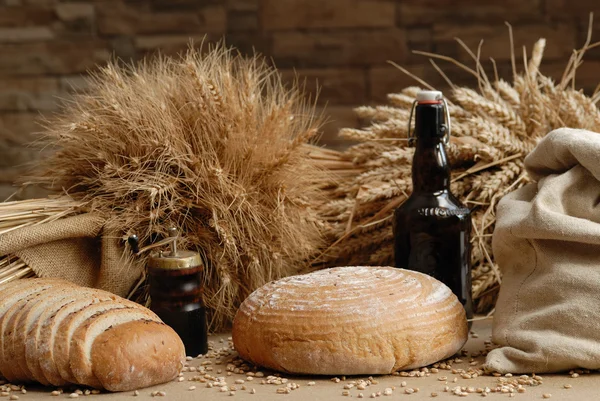 Pão fresco assado com hastes de trigo e garrafa de urso Fotografias De Stock Royalty-Free