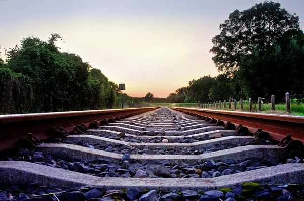 Järnvägsspår med blekt pastell solnedgång — Stockfoto