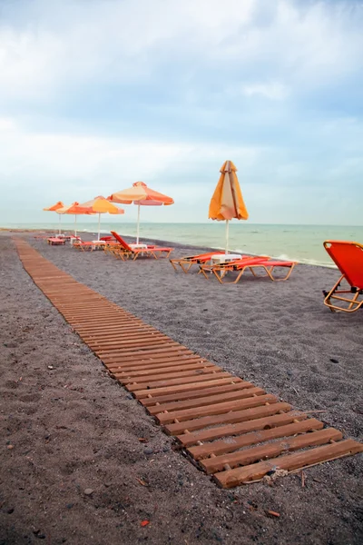 Praia com cadeiras de sol e passarela — Fotografia de Stock