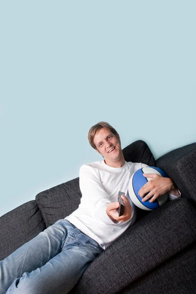 Счастливый молодой человек смотрит спорт по телевизору — стоковое фото