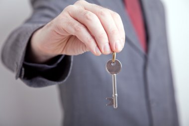 Man in suit holding out key clipart