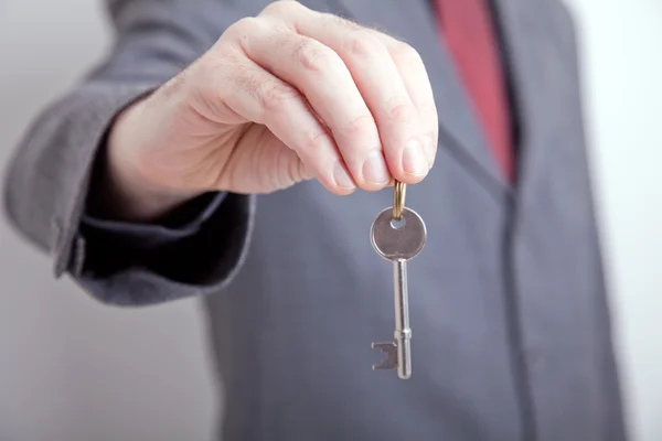 stock image Man in suit holding out key