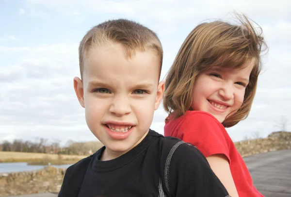 Dwoje dzieci uśmiech do kamery w parku — Zdjęcie stockowe