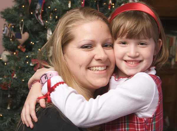 Mamma och barn kram av en julgran — Stockfoto