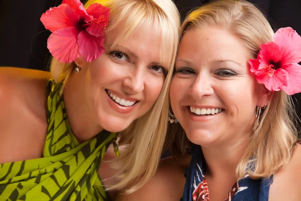 Две улыбающиеся девушки с цветками гибискуса — стоковое фото