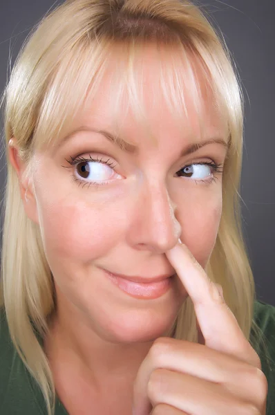 Blond kobieta z palcem w nosie — Zdjęcie stockowe