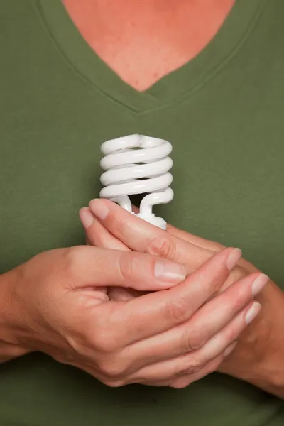 Kobieta ręce, trzymając żarówka energooszczędna — Zdjęcie stockowe