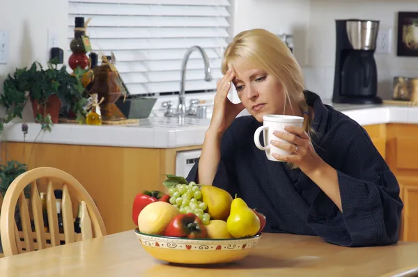 Стрессовая женщина держит голову на кухне — стоковое фото
