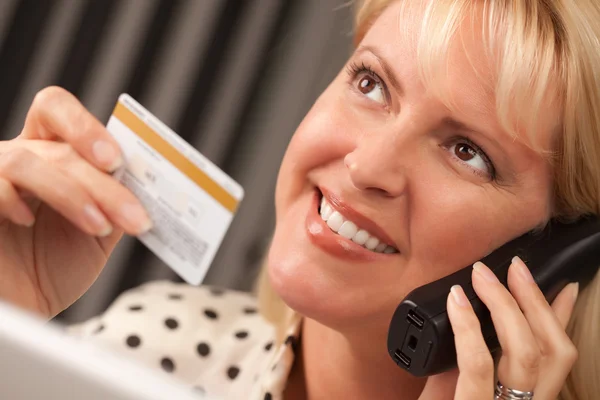 Mujer en su computadora portátil que sostiene la tarjeta de crédito —  Fotos de Stock