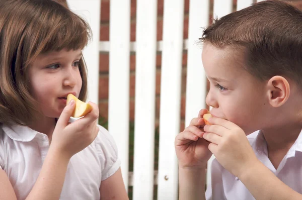 Hermana y hermano divirtiéndose comiendo una manzana —  Fotos de Stock