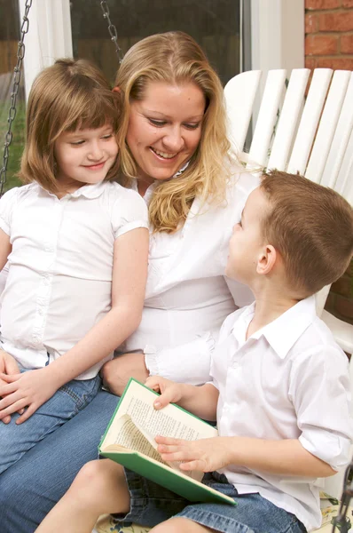 Genç erkek kardeşi ve kız kardeşi anne ile kitapları okur — Stok fotoğraf