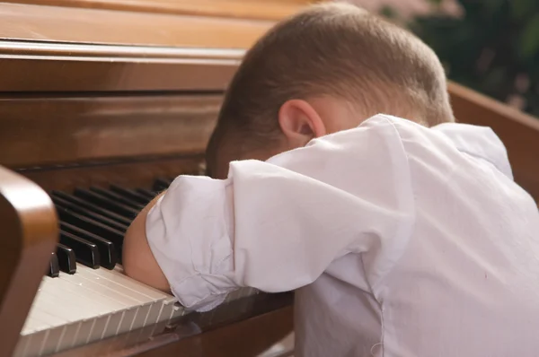 Ledsen pojke med huvud på piano — Stockfoto