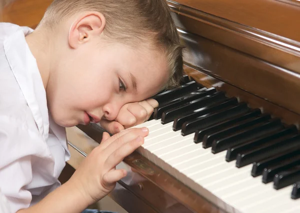 Jeune garçon avec la tête à la main jouant du piano — Photo