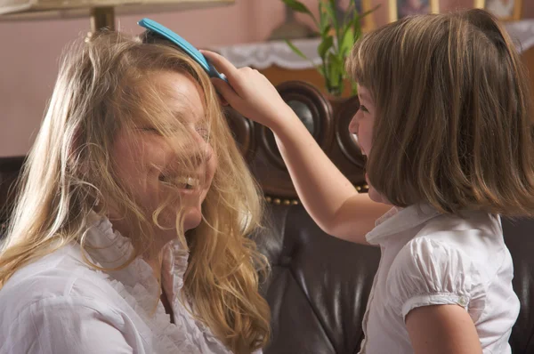 Ung flicka borstar mammas hår — Stockfoto