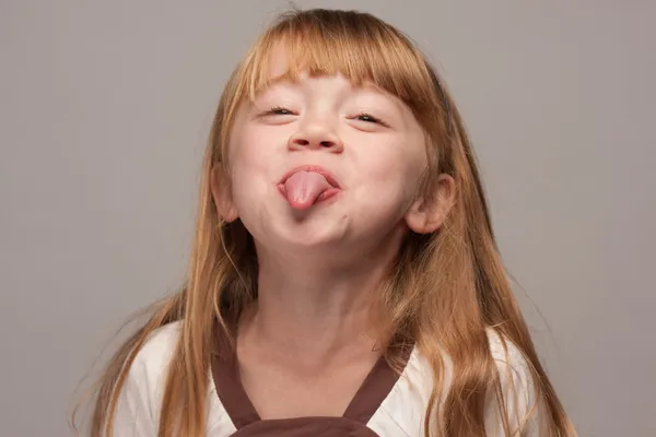 Menina de cabelos vermelhos com língua colando para fora — Fotografia de Stock