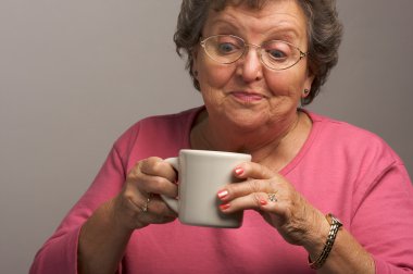 Senior Woman on a Gray Background Enjoys Coffee clipart