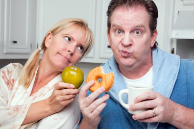 Couple in Kitchen with Fruit and Donuts clipart