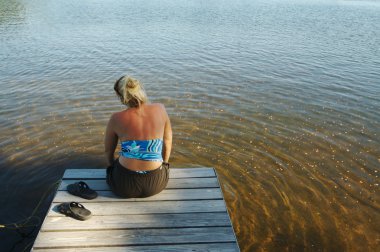 Blonde Woman Relaxing on the Dock clipart