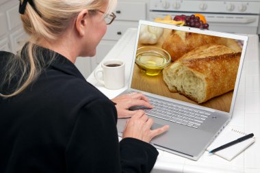 Woman In Kitchen Using Laptop Computer with Bread and Olive Oil on Screen