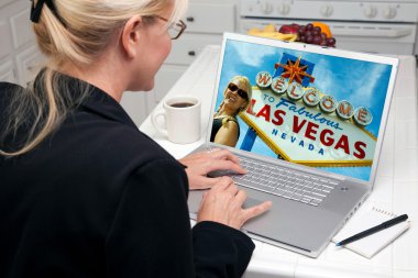 Woman In Kitchen Using Laptop with Las Vegas Sign on Screen clipart