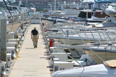 Man Walking the Dock Surrounded by Boats clipart