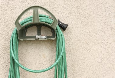 Garden Hose Hanging on Stucco Wall clipart