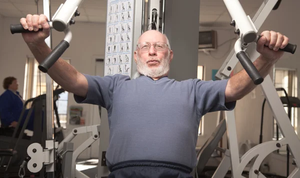 Hombre adulto mayor haciendo ejercicio en el gimnasio . — Foto de Stock