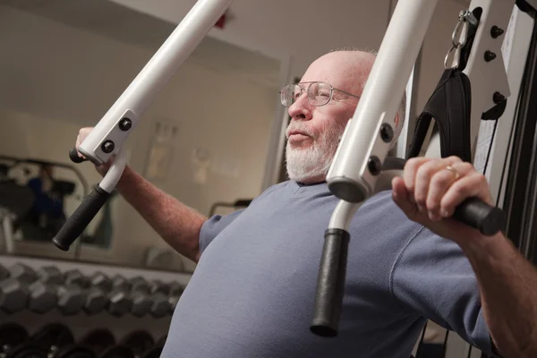 Hombre adulto mayor haciendo ejercicio en el gimnasio . — Foto de Stock