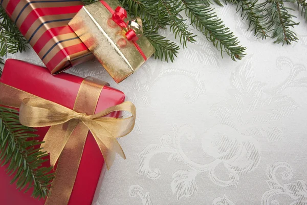 Silk karácsonyi ajándékok háttér és a fenyő brranches — Stock Fotó