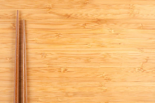 Pałeczek do jedzenia na tle powierzchni bambusa — Zdjęcie stockowe