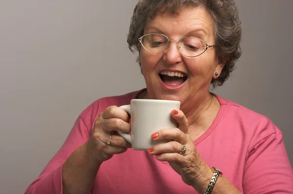 Starší žena na šedém pozadí má káva — Stock fotografie