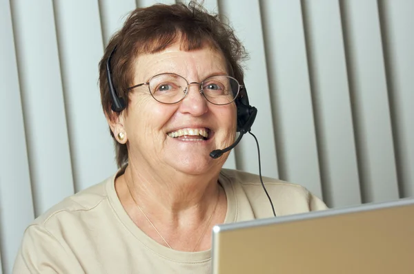 Adulto mayor sonriente con auriculares telefónicos —  Fotos de Stock