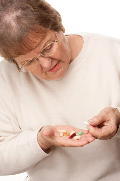 Привлекательная пожилая женщина, принимающая таблетки изолировано — стоковое фото