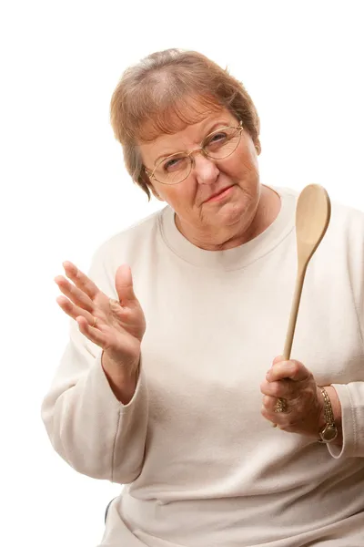 Mujer mayor trastornada con una cuchara de madera aislada —  Fotos de Stock